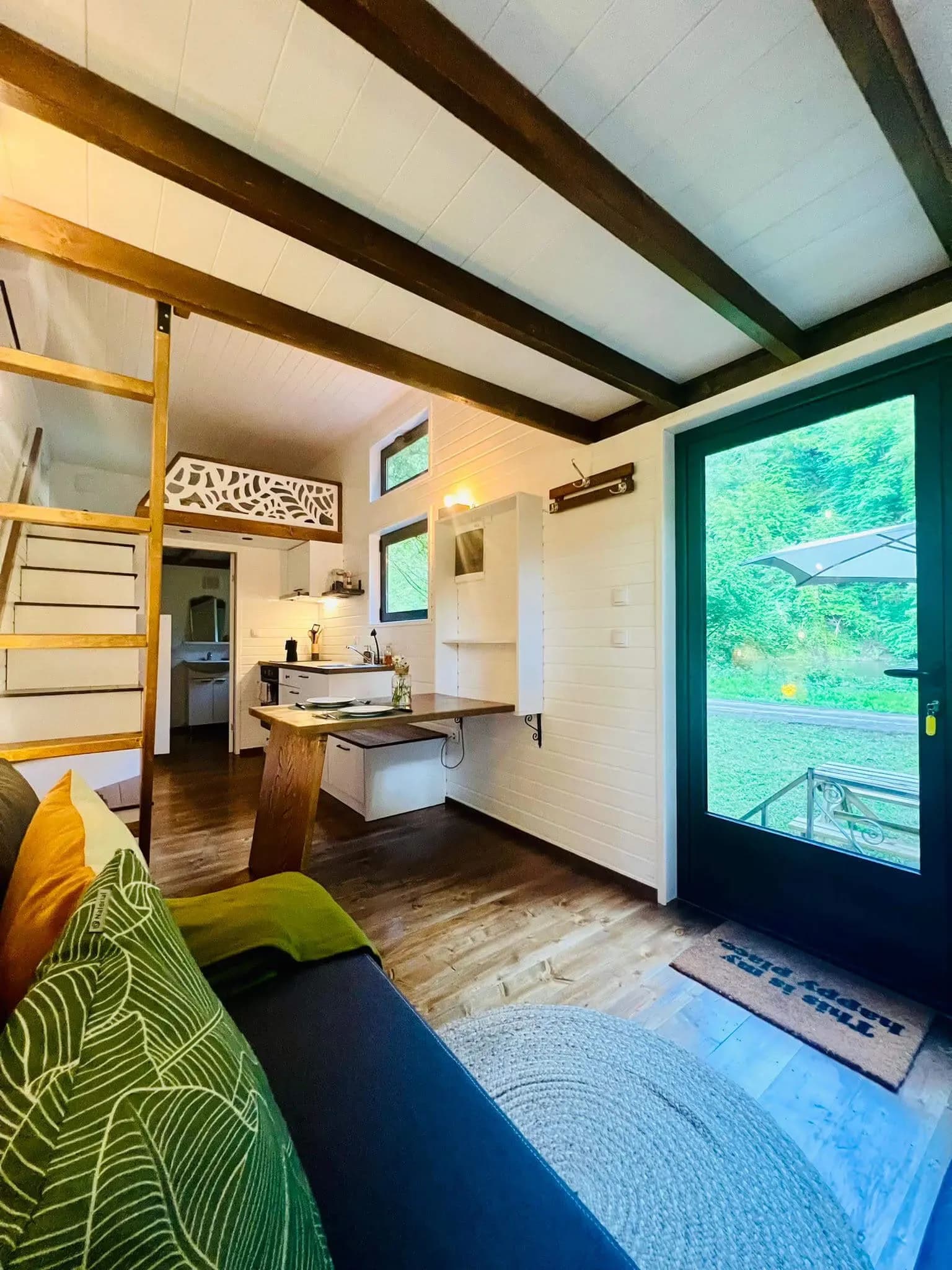 Séjour du Sharewood : mezzanine, échelle et porte vitrée ouverte sur la forêt