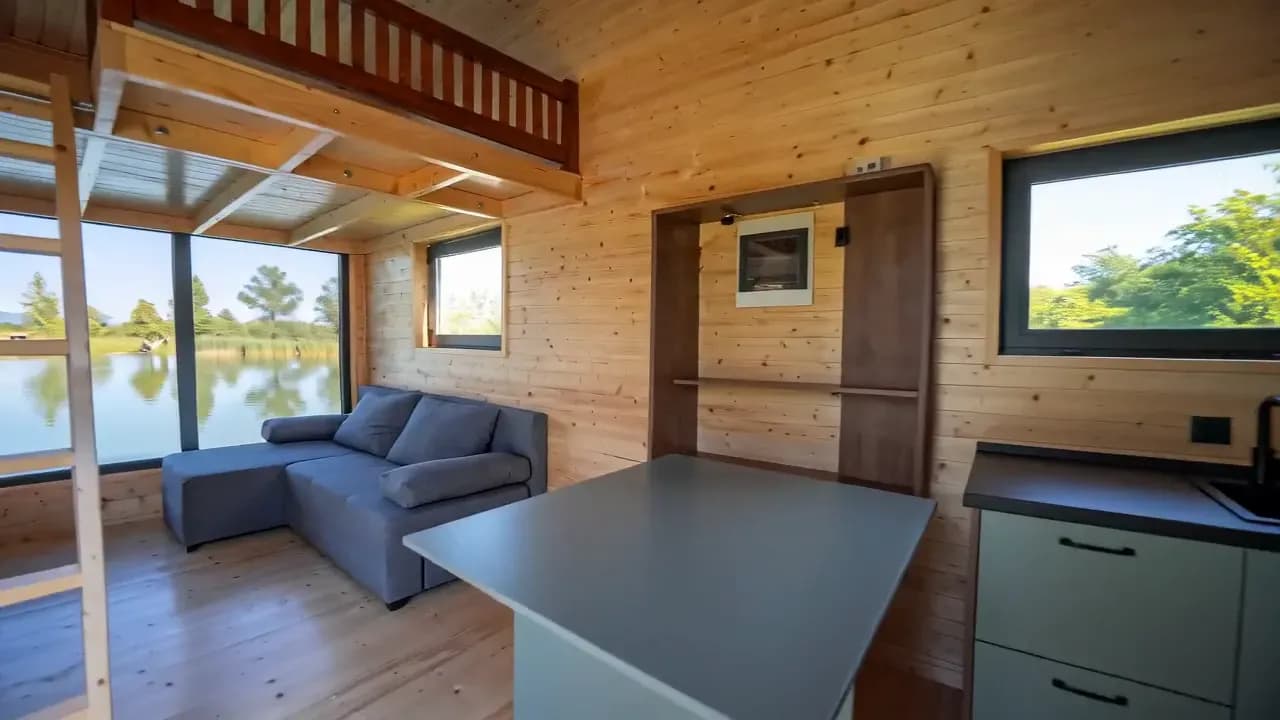 Séjour avec canapé, échelle vers la mezzanine et vue sur le lac