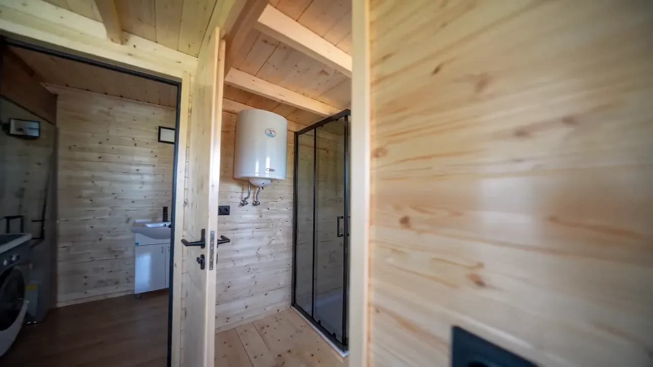 Salle de bain avec douche vitrée, lavabo et chauffe-eau