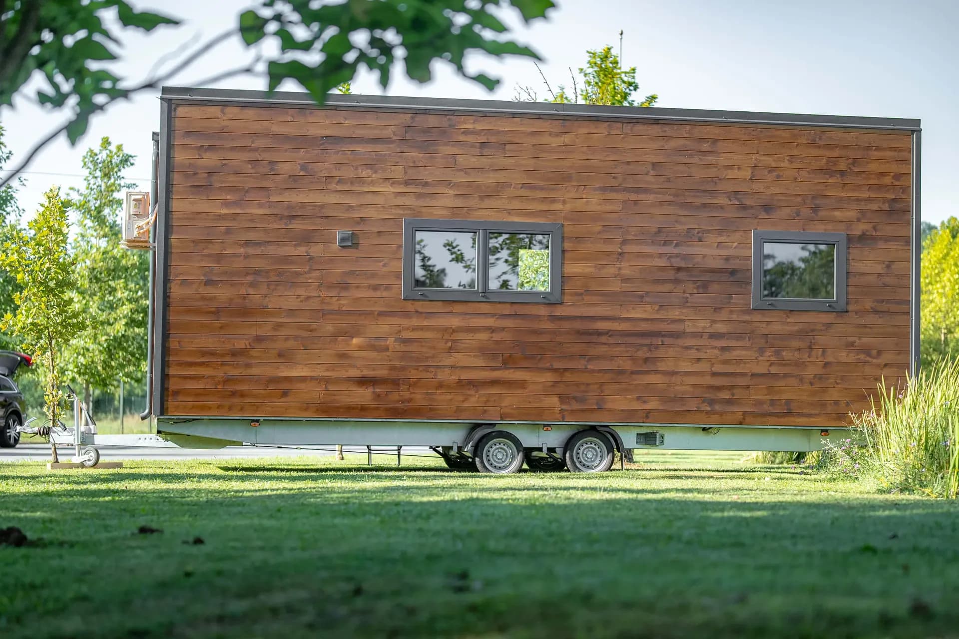 Façade longue en bois du Skywood sur sa remorque, dans une prairie