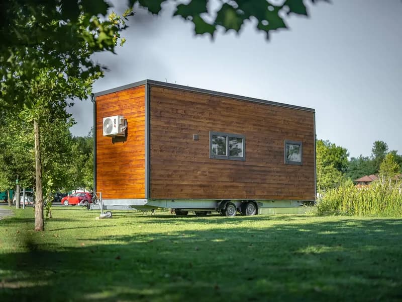 Façade longue en bois du Skywood sur sa remorque, dans une prairie